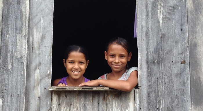 Sisters aged 8 and 9 take care of their brother, who is under 5, while their mother works.