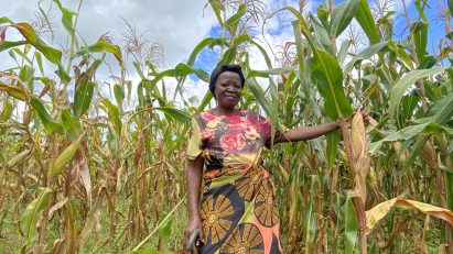 A COMACO conservationalist smiles amongst tall crops