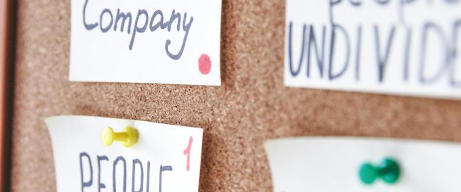 labels on cork board, one says 'human oriented company', another 'people first'