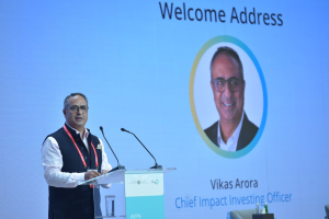 Vikas Arora stands at a lecturn in the plenary hall at AVPN's impact investing day